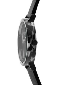 Ronde klok met een matte zwarte band, transparante behuizing met camouflagepatroon en een donkere wijzerplaat. Inclusief zilveren uurmarkeringen en een zijwaartse kroon.