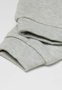 Szare prążkowane rękawy długiego rękawa bluzy lub kaptura, przedstawione złożone na jednolitym jasnym tle.