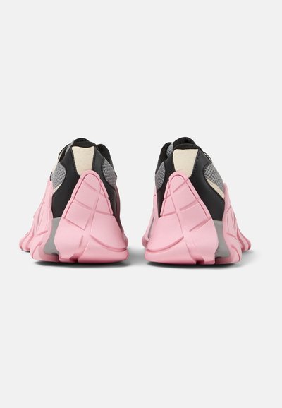 Rear view of athletic shoes featuring a pink rubber sole, black upper with mesh accents, and textured detailing on sides.