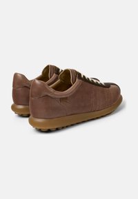 Zapatillas deportivas de cuero marrón con acabado texturizado; cuentan con una suela flexible, detalles oscuros en contraste y cierre clásico de cordones.