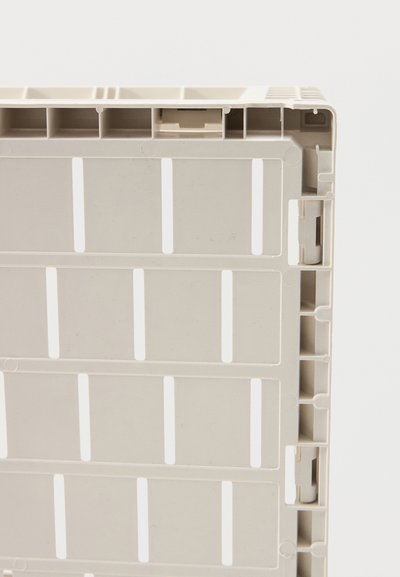 Palette en plastique beige avec un design à grille rectangulaire et sections creuses sur un fond blanc, montrant les coins et les bords latéraux.