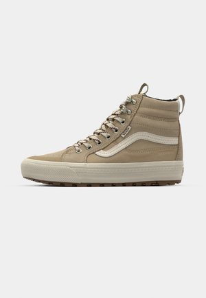 Høje beige Vans sneakers med en tekstureret ruskindssoverdel, hvid læder sidestreg, metalliske snørehuller og en gummisål med brun traction.