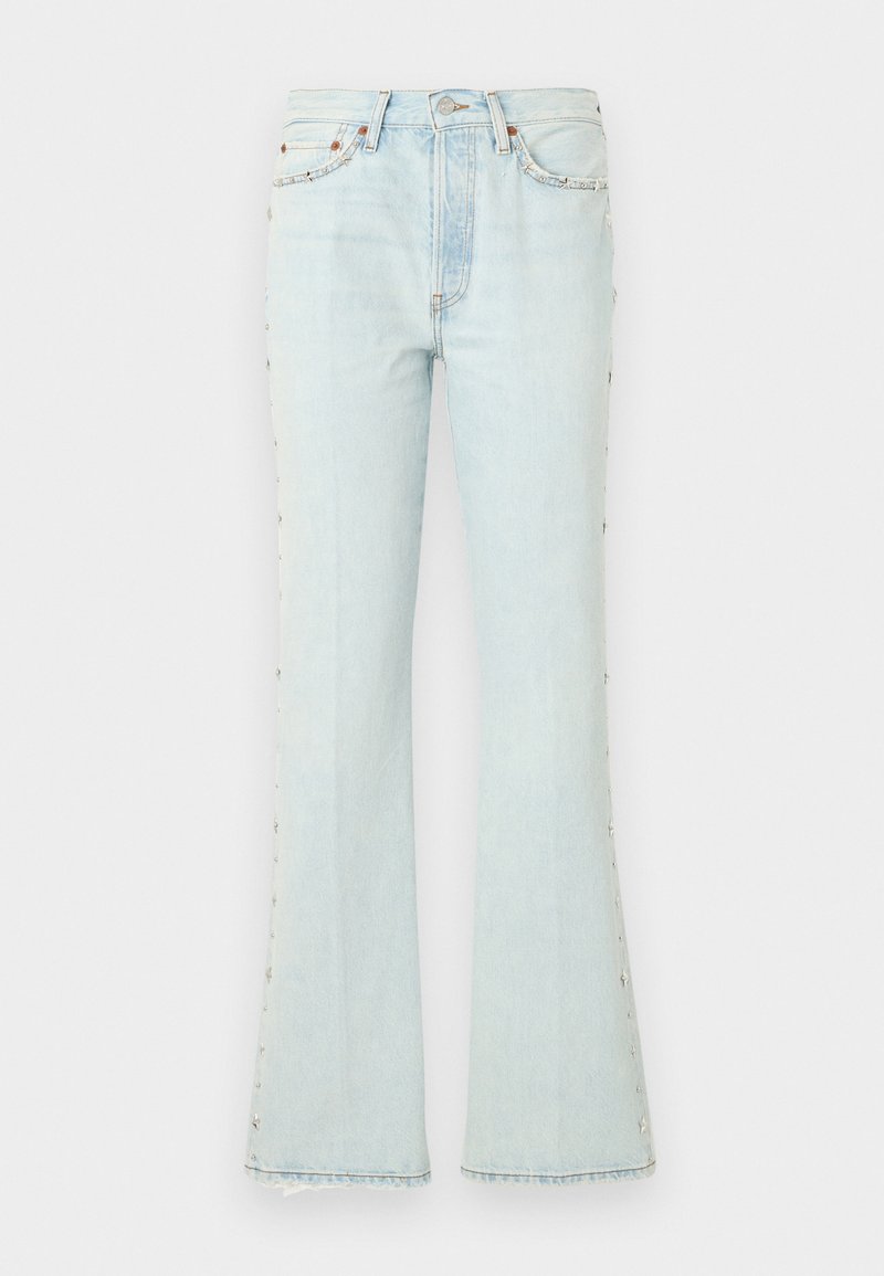 Jean en denim bleu clair taille haute avec jambes évasées, poches avant et arrière, fermeture par bouton et zip, et clous étoiles en métal le long des coutures extérieures.