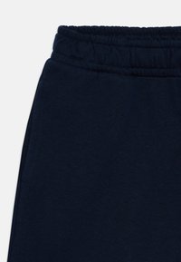 Marinblå sweatpants med elastisk midja, mjukt bomullsmaterial och en slät yta. Har sidofickor och minimala sömmar.