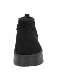 Černé semišové kotníkové boty s kulatou špičkou, elastickými bočními panely a texturovanou černou gumovou podrážkou. Mají také zadní poutko pro snadné obouvání.