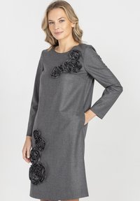 Szara sukienka wykonana z teksturowanej tkaniny, zdobiona du�żymi czarnymi różami z tkaniny po lewej stronie oraz rękawami o długości do łokcia.