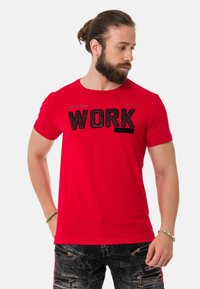 Rotes Baumwoll-T-Shirt mit kurzen Ärmeln, das mit dem auffälligen schwarzen Text "WORK HARD" versehen ist. Glatte Textur, runder Halsausschnitt, taillierte Passform.