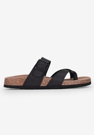 Black sandal with cork midsole, featuring a wide strap with a buckle and crossed toe straps. Flat sole design with rubber bottom.