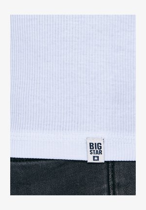 Fehér bordázott szövet, felette egy kis "BIG STAR" címke, az alsó szélén sötét farmeranyag.