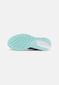 Semelle d'une chaussure de course avec une semelle d'un bleu clair texturé et une zone de support de la voûte plantaire blanche sur un fond blanc uni.