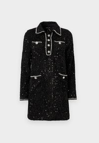 Vestido preto com lantejoulas, de gola com colarinho, com cinco botões à frente e dois bolsos, apresentando uma borda prateada e adornos redondos.