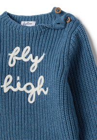Suéter de punto azul con el texto bordado en blanco "fly high" y dos botones de madera en el hombro izquierdo para el cierre.