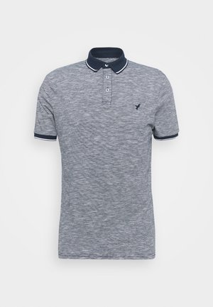 Harmaa pikeepaita, jossa on teksturoitu kangas, laivastonsininen kaulus, kolmen napin nappilista ja pieni logo rinnassa.