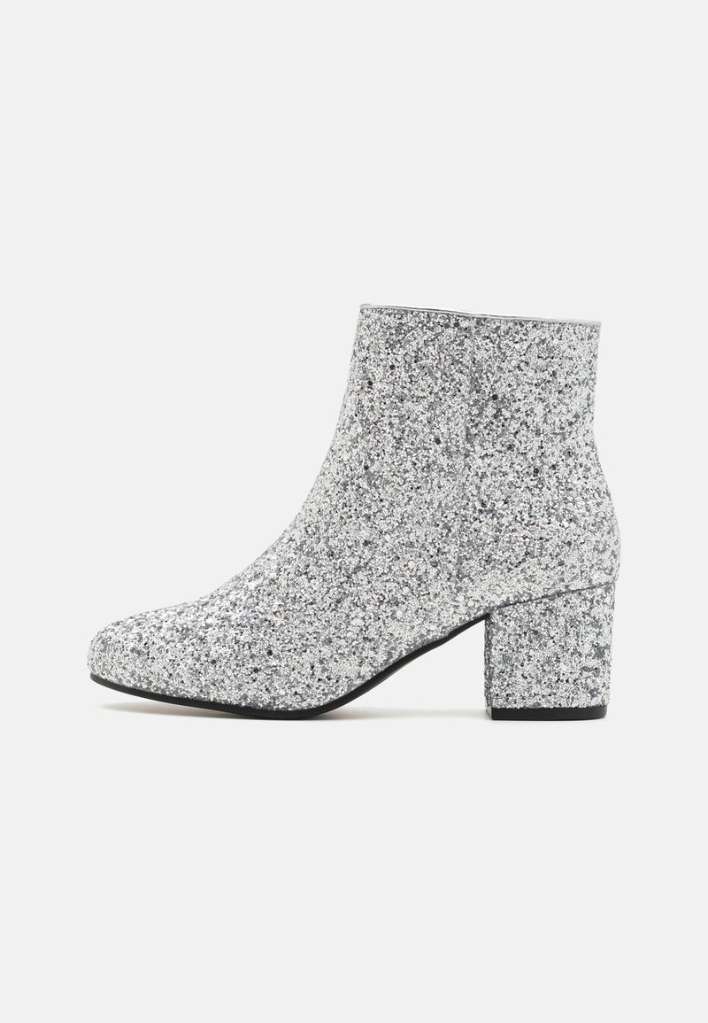 Silver glitter ankle boot with a rounded toe, block heel, and smooth texture. Features a shimmering surface with no visible hardware.