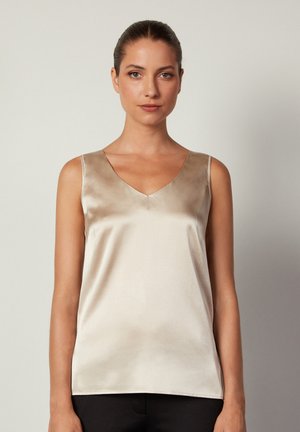 Top sans manches satiné de couleur beige avec un décolleté en V, texture lisse et silhouette ajustée. Design minimaliste, sans motifs ni accents visibles.