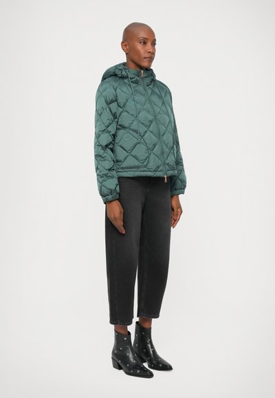 Quilted teal pufferjakke med hætte, der har snoretræk og et cropped design. Kombinationen med højere sorte jeans og sorte ankelstøvler med nitter.