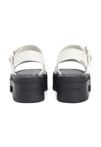 Λευκά πλατφόρμα σανδάλια με ρυθμιζόμενα λουριά αστραγάλου, μαύρες λαστιχένιες σόλες και ανάγλυφο λογότυπο "TOMMY JEANS". Λείες και ματ υφές.