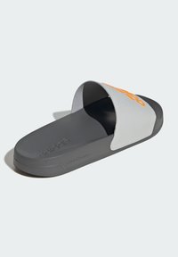 Slide sandal with a gray upper and orange logo, textured sole, and soft foam cushioning for comfort. Features an open toe design.
