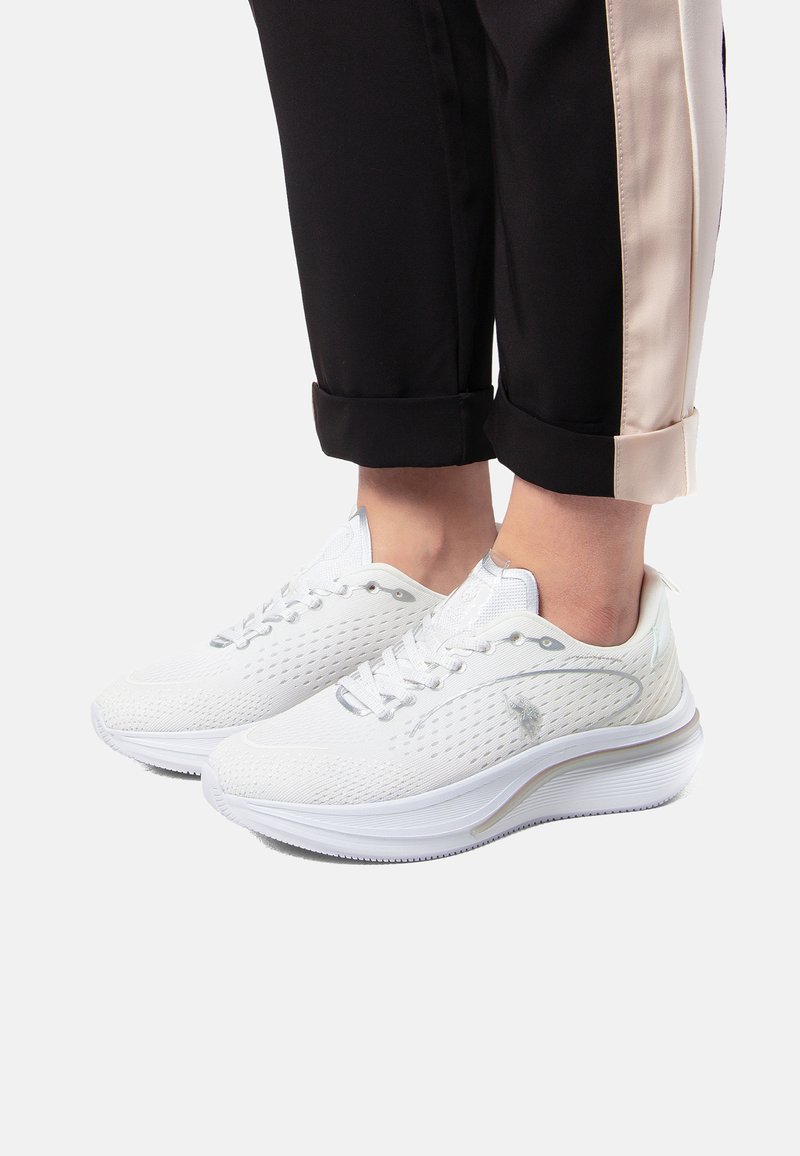 Vita sportskor med perforerat överdel, texturerad design och kontrasterande sula. Har grå accentuer och traditionellt snörsystem.