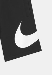 Czarne sportowe szorty z miękkiego materiału, z wyraźnym białym logo Nike po boku oraz standardowym paskiem w talii z kieszeniami.