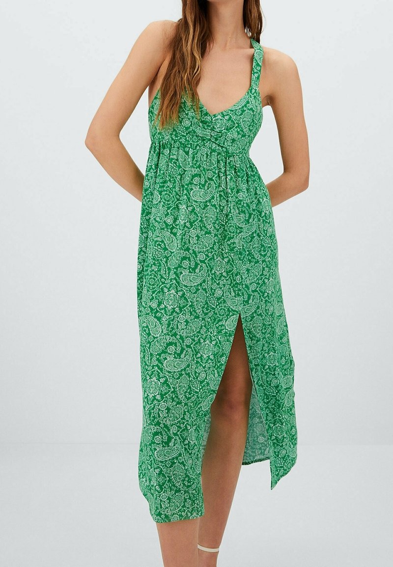 Vihreä paisley-kuvioinen mekko, jossa on V-aukko, hihaton malli ja sivuaukko. Valmistettu kevyestä materiaalista, joka takaa ilmavan istuvuuden.