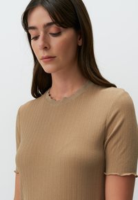 Lichtbruine geribbelde gebreide t-shirt met een scalloped halslijn en korte mouwen, gemaakt van een zachte, rekbare stof.
