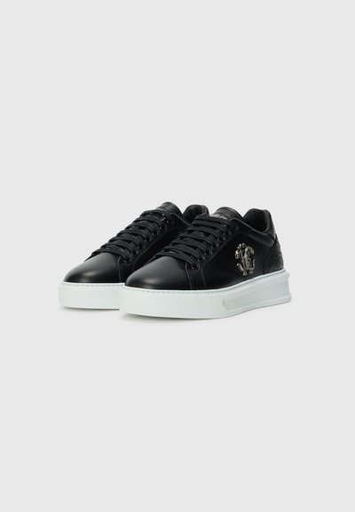 Baskets en cuir noir avec un accent texturé au talon, semelle en caoutchouc blanche et détail du logo sur le côté. Bout arrondi et design à lacets.