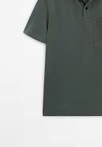 Polo à manches courtes vert foncé avec deux boutons noirs et une poche poitrine, présenté sur un fond blanc.