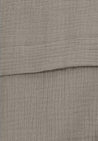 Light brown textured fabric with a crinkled surface, displaying a grid pattern. Material appears soft and slightly coarse.
