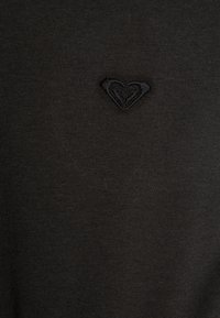 Schwarzer gestrickter Pullover mit einem kleinen gestickten Herzlogo in der Mitte, hergestellt aus einem weichen, glatten Stoff mit feiner Textur.