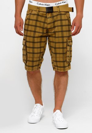 Khaki plaid cargo shorts with black accents, featuring side pockets and a belt with a Calvin Klein logo. Material appears lightweight and durable.