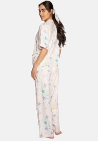 Short-sleeve pajama set in soft fabric, featuring a pastel star pattern in purple, blue, and yellow on a light background.