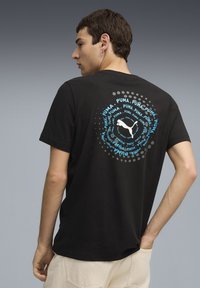 Camiseta de algodón negra con un gráfico circular de texto azul y gris y un logotipo en la parte trasera. Manga corta y corte relajado.