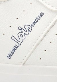 Zapatilla de cuero blanca con perforaciones para transpirabilidad. El texto azul del logo dice "Lois Original Desde 1962" en el lateral.