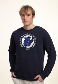 Felpa blu navy in misto cotone, con una stampa grafica rotonda che presenta una mascotte di diavolo blu e bianco e del testo, polsini e colletto a costine.