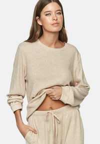 Beige geribde pullover trui met lange mouwen, ronde halslijn en een ontspannen pasvorm. Gecombineerd met bijpassende beige sweatpants met trekkoord.