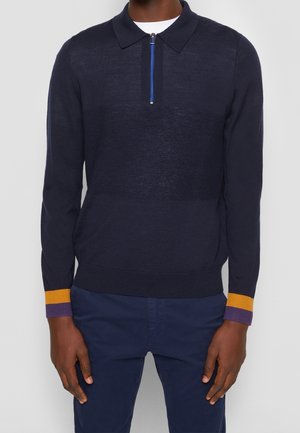 Navy knit pullover with a zippered collar, featuring textured middle section and color block accents in yellow and purple at the cuffs.