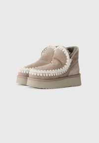 Pantofi din suede într-o nuanță deschisă de taupe, având o broderie decorativă groasă de culoare crem pe guler, căptușeală texturată și o talpă chunky din cauciuc.