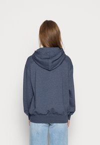 Sudadera con capucha de color azul marino, de corte relajado, con puños y dobladillo acanalados. Textura suave con una capucha grande de doble capa.
