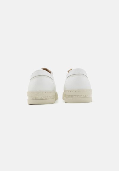 Zapatos de cuero blanco con acabado texturizado, que cuentan con una suela de goma beige y el logo "WEITZMAN" en el talón trasero. Diseño minimalista.