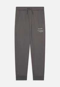 Pantalon de survêtement gris avec une taille élastique et un cordon de serrage. Comprend des poches latérales et un logo imprimé blanc sur la cuisse gauche. Poignets côtelés.