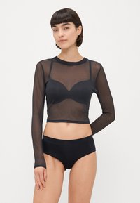 Czarny siatkowy krótki top z długim rękawem i zaokrąglonym dekoltem, z przezroczystego materiału, do kompletu dopasowane czarne majtki, o gładkiej fakturze i subtelnym wzorze.