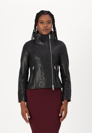 Veste en cuir noir avec un col haut, fermeture éclair à l'avant et trois poches zippées. Design ajusté avec une texture lisse. Le modèle porte une robe bordeaux à côtes.