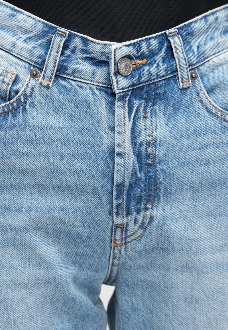 Light blue denim jeans with a classic fit, featuring a button closure, visible stitching, and subtle fading in the fabric texture.