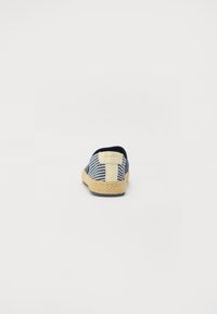 Chaussure à enfiler en tissu rayé avec un dessus bleu marine, des détails en jute sur la semelle extérieure et un accent crème à l'arrière.