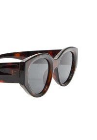 Okulary przeciwsłoneczne w stylu żółwia o dużych, zaokrąglonych szkłach, grubych oprawkach i błyszczącym wykończeniu. Posiadają subtelny geometryczny wzór.