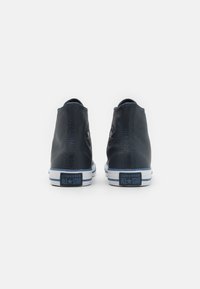 Tumes sinised kõrged tossud, mis on valmistatud tekstureeritud nahast ja millel on valged kummitaldad. Omab pahkluu lõiget, siniseid aktsente ning Converse'i logo taga.