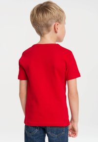 Red cotton t-shirt with short sleeves and a crew neckline. Seen from the back, it has a classic design with plain texture.