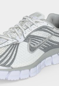 Άσπρο και γκρι παπούτσι Nike για τρέξιμο με επάνω μέρος από δίχτυ, κλείσιμο με κορδόνια, ορατό λογότυπο Nike και διαχωρισμένη λευκή σόλα.