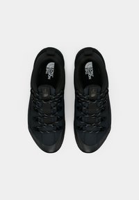 Črni športni čevlji z teksturiranim zgornjim delom, z vezalkami, okrepljenim prstom in gumijastim podplatom za oprijem.